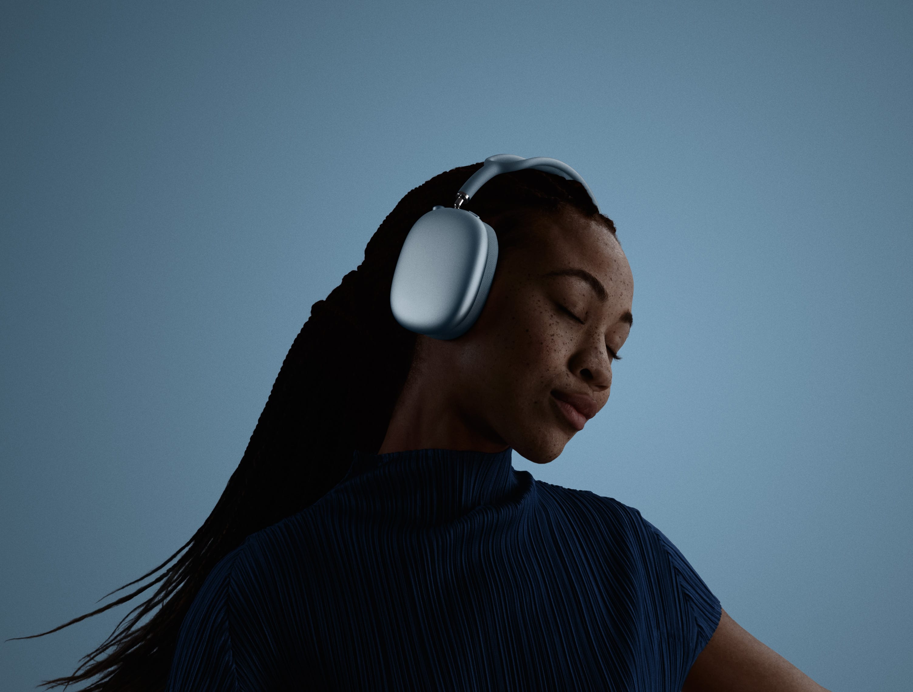 A woman wearing sky blue Apple AirPods Max over-ear headphones
