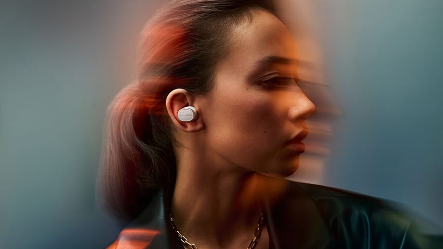 A woman in profile wearing a white earbud, caught in motion blur
